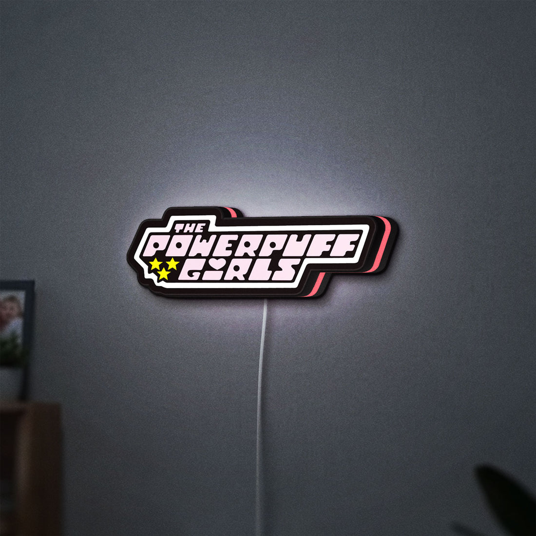 The Powerpuff Girls LED lightbox hanging on a wall with pink glow