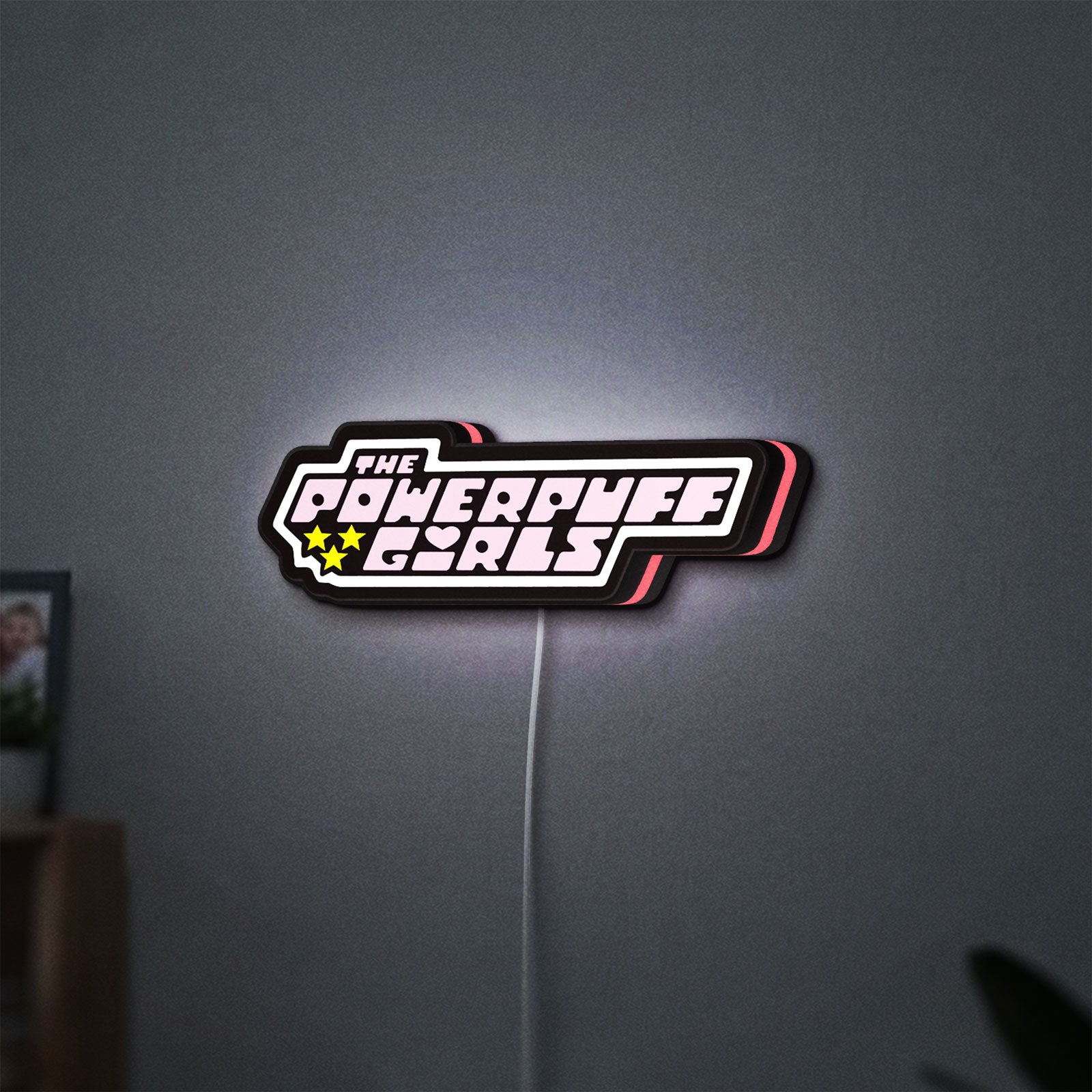The Powerpuff Girls LED lightbox hanging on a wall with pink glow
