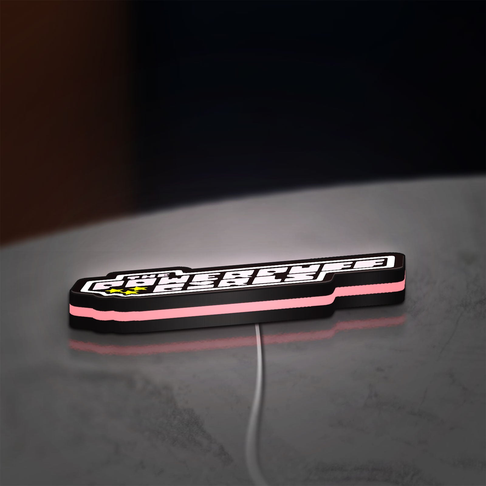 The Powerpuff Girls LED lightbox lying flat on a desk with pink glow