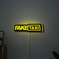 Fake Taxi LED lightbox hanging on a wall with yellow glow
