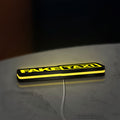 Fake Taxi LED lightbox lying flat on a desk with yellow glow