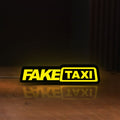 Front view of Fake Taxi LED lightbox sign glowing on a wooden desk