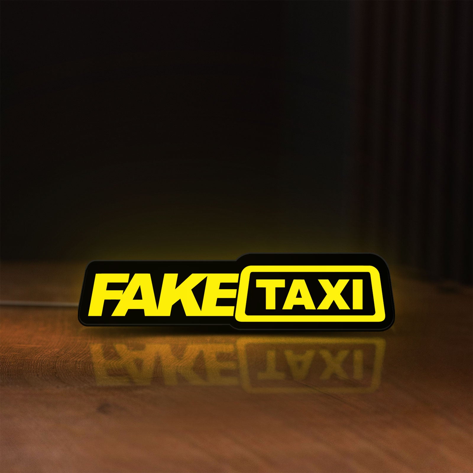 Front view of Fake Taxi LED lightbox sign glowing on a wooden desk