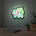 Bulbasaur LED lightbox hanging on a room wall with soft green light