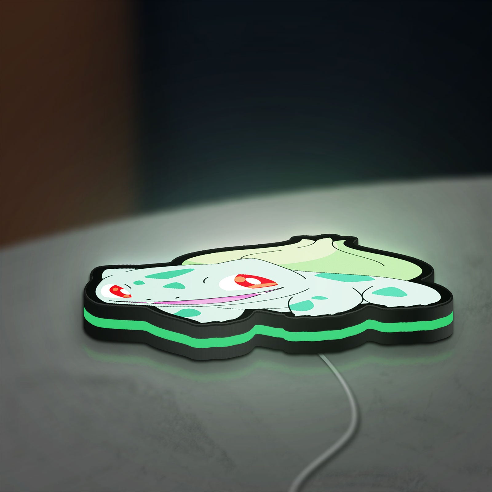 Bulbasaur LED lightbox lying flat on a desk with green glow