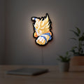 Goku LED lightbox hanging on a room wall with soft yellow light