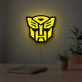 Autobots LED lightbox hanging on a room wall with soft yellow light