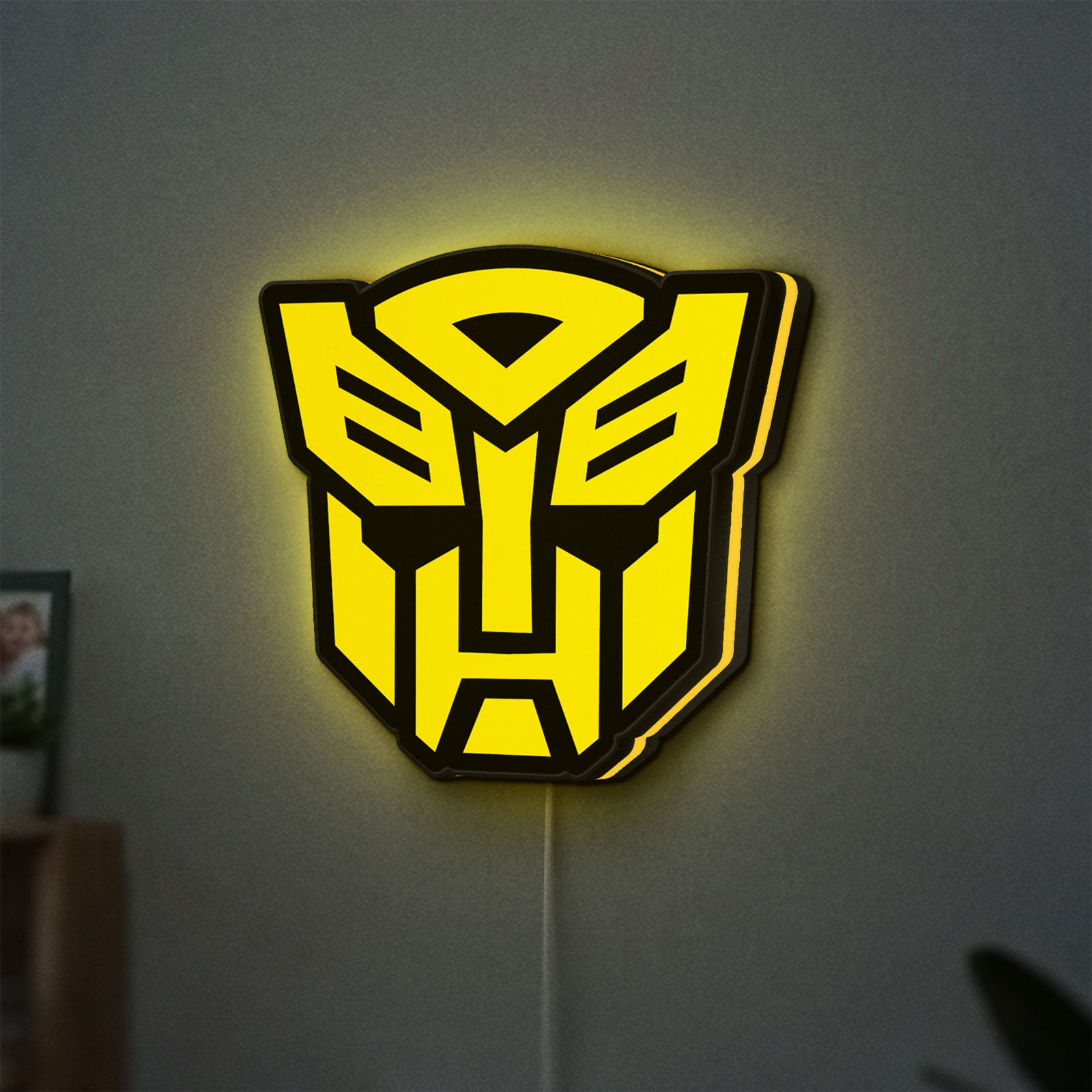 Autobots LED lightbox hanging on a wall with yellow glow
