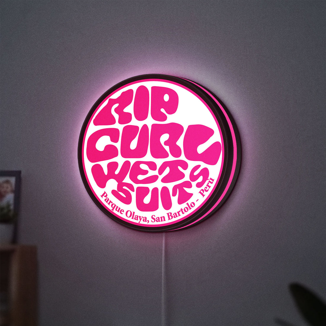 Rip Curl LED lightbox hanging on a wall with pink glow