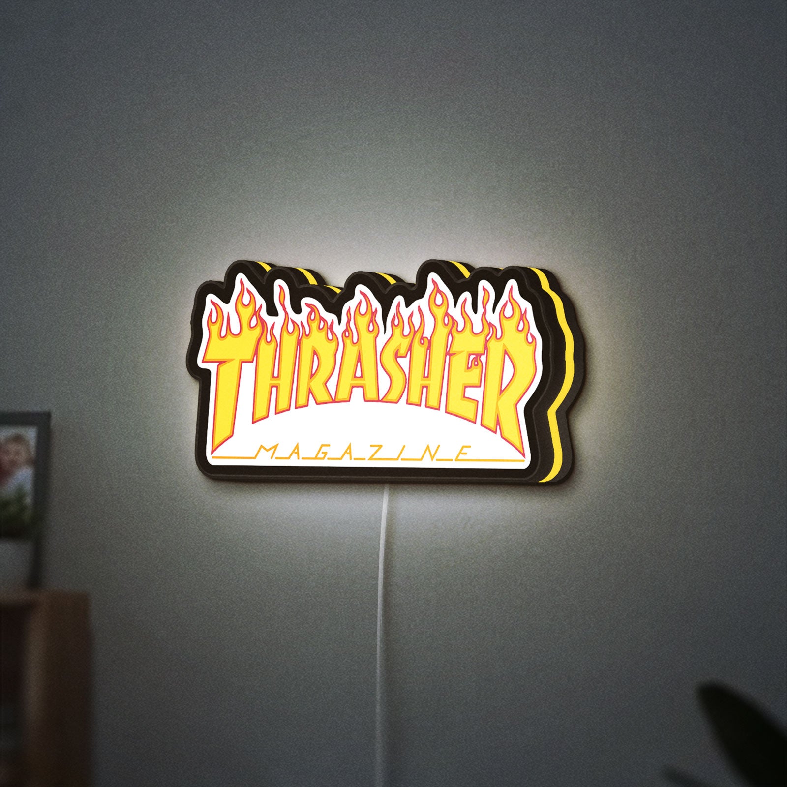 Thrasher Magazine LED lightbox hanging on a wall with yellow glow
