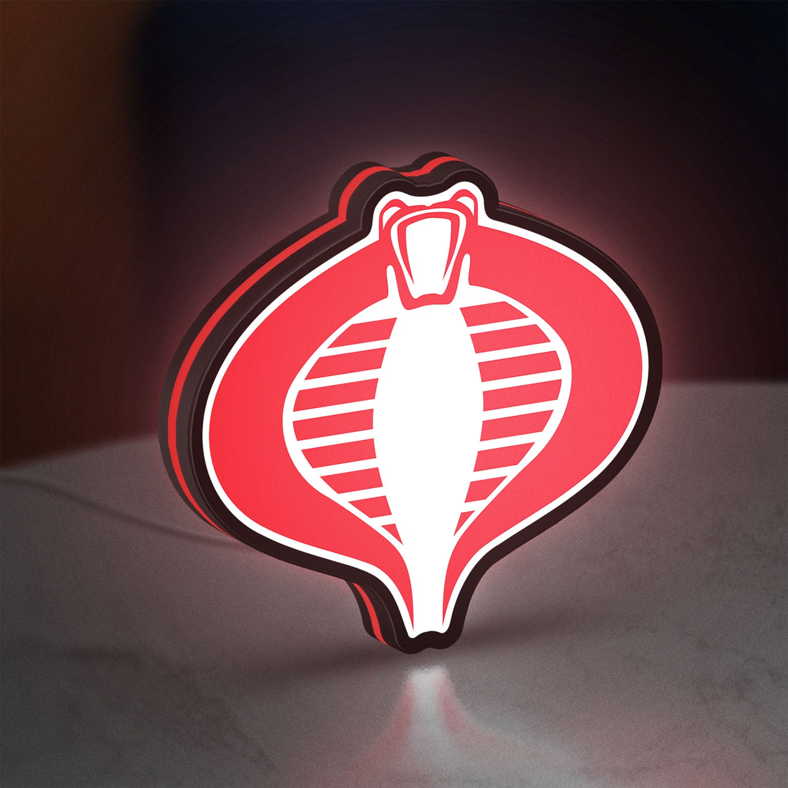 G.I. Joe Cobra LED lightbox standing on a desk from an angled side view with red glow