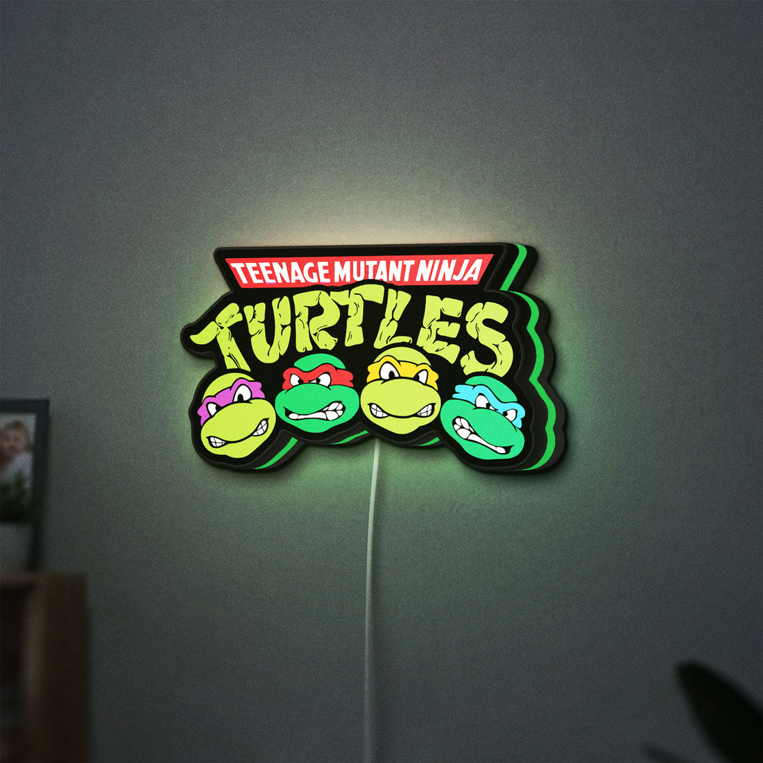 Teenage Mutant Ninja Turtles LED lightbox hanging on a wall with green glow