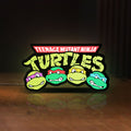 Front view of Teenage Mutant Ninja Turtles LED lightbox sign glowing on a wooden desk