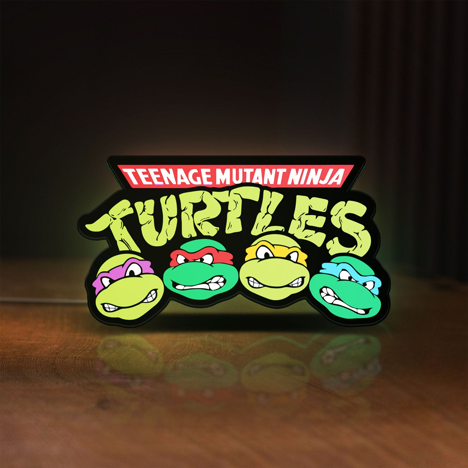 Front view of Teenage Mutant Ninja Turtles LED lightbox sign glowing on a wooden desk