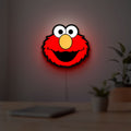 Elmo LED lightbox hanging on a room wall with soft red light
