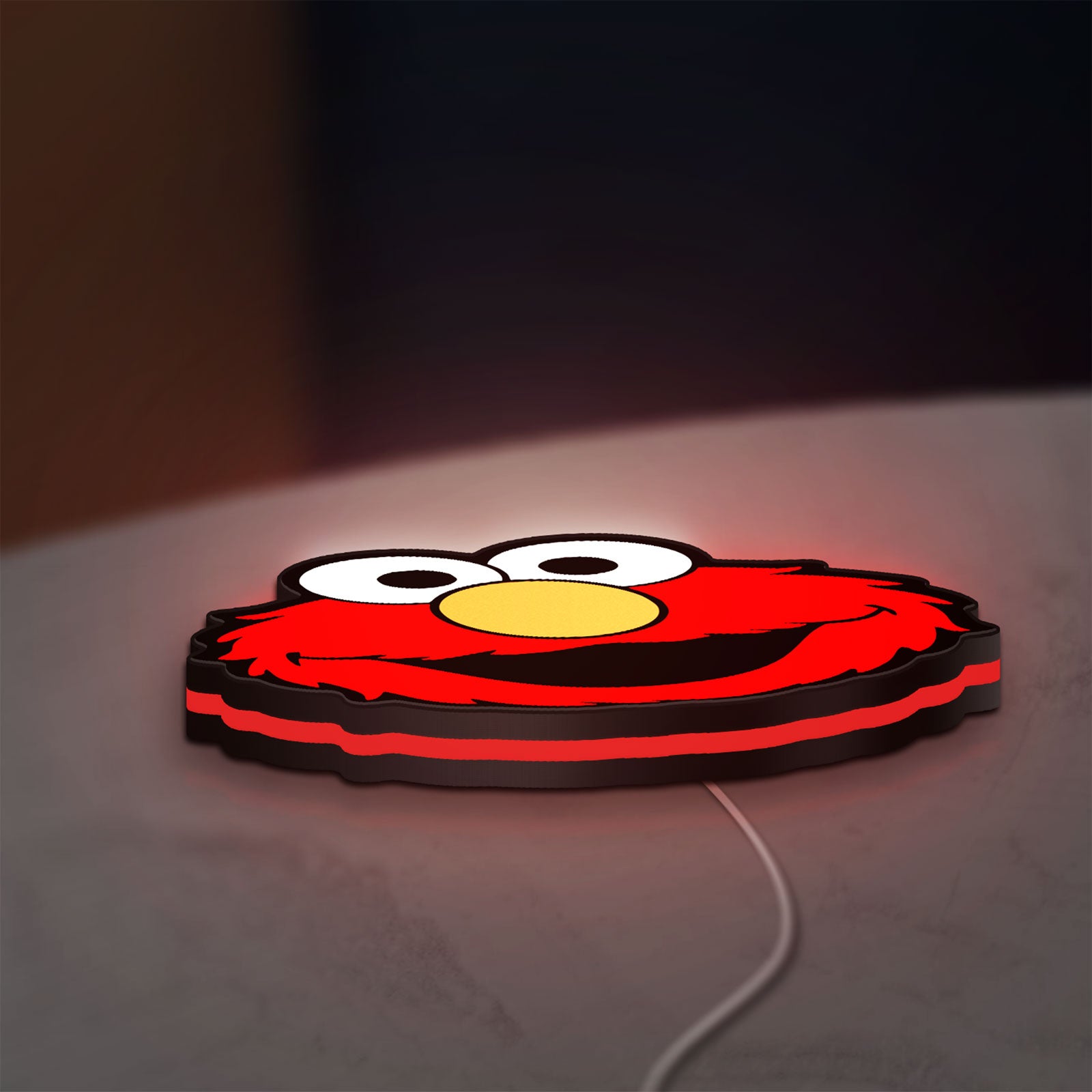 Elmo LED lightbox lying flat on a desk with red glow