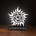 Front view of Supernatural LED lightbox sign glowing on a wooden desk