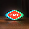 Front view of TRT LED lightbox sign glowing on a wooden desk
