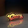 Cheers LED lightbox standing on a desk from an angled side view with yellow glow