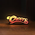 Front view of Cheers LED lightbox sign glowing on a wooden desk