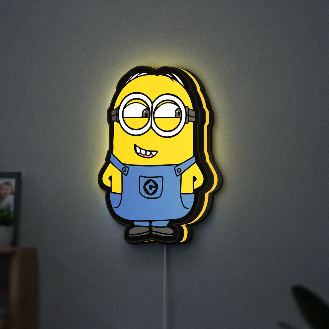 Minions Character LED lightbox hanging on a wall with yellow glow