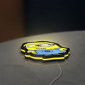 Minions Character LED lightbox lying flat on a desk with yellow glow
