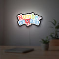 Numberblocks LED lightbox hanging on a room wall with soft white light