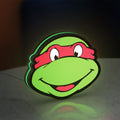 Teenage Mutant Ninja Turtles LED lightbox standing on a desk from an angled side view with green glow
