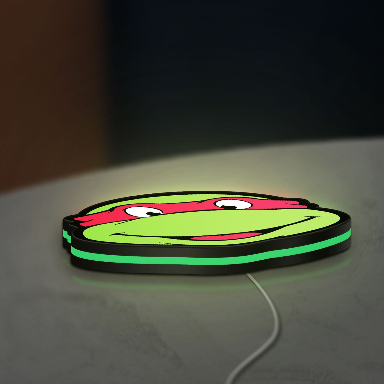Teenage Mutant Ninja Turtles LED lightbox lying flat on a desk with green glow