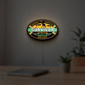 Survivor Africa LED lightbox hanging on a room wall with soft orange light