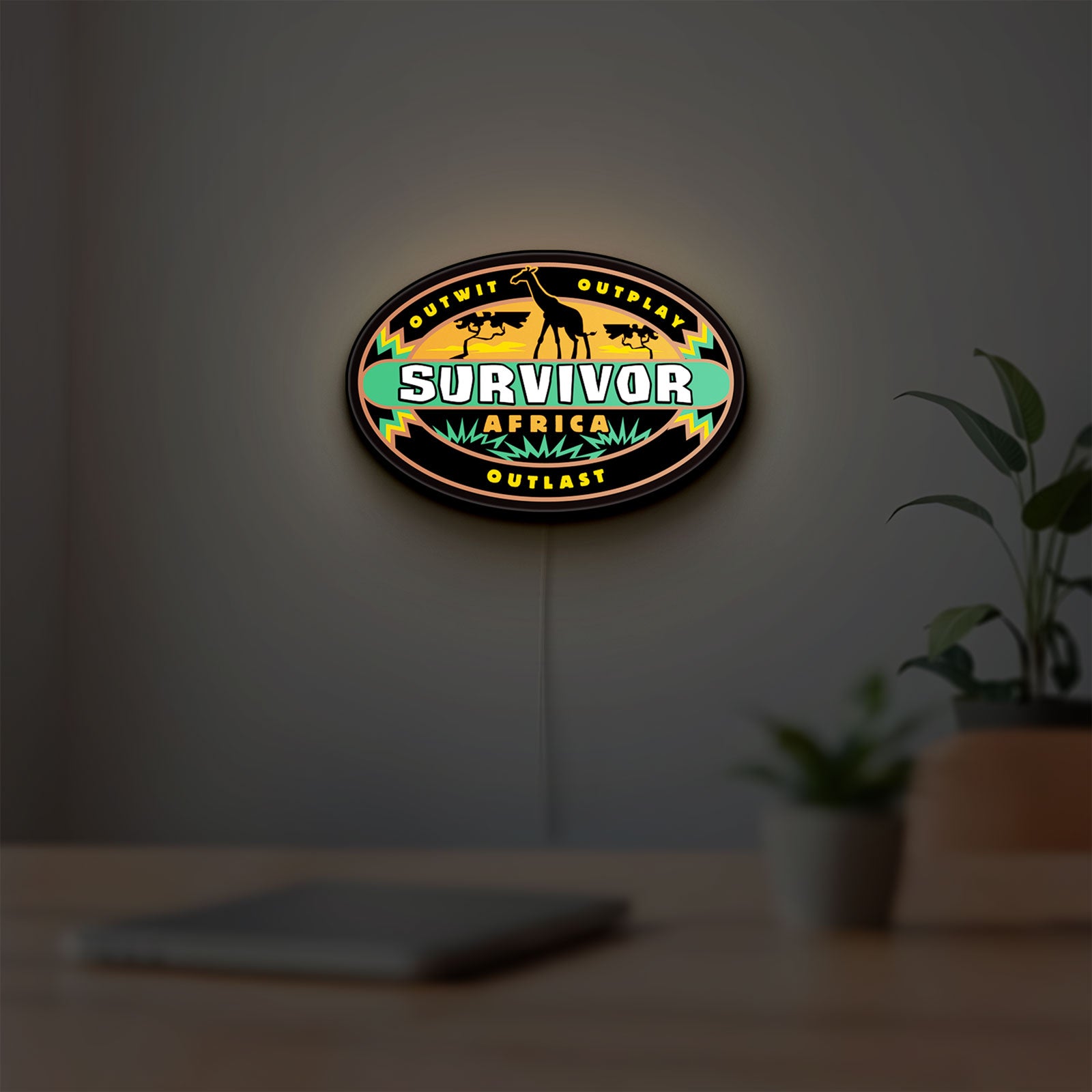 Survivor Africa LED lightbox hanging on a room wall with soft orange light