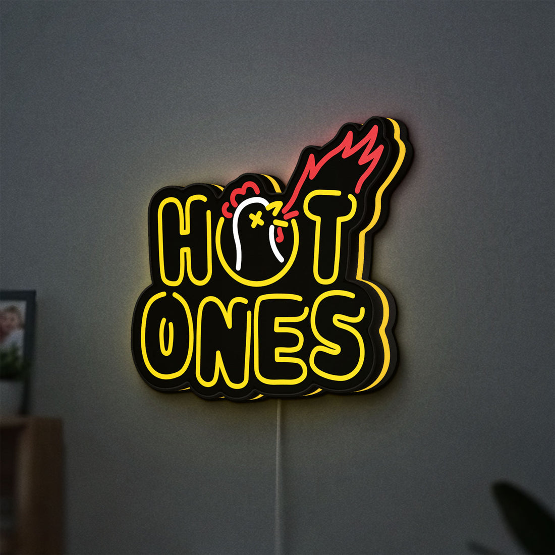 Hot Ones LED lightbox hanging on a wall with yellow glow