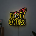 Hot Ones LED lightbox hanging on a wall with yellow glow