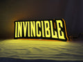 Invincible LED Sign (40cm) - Illuminated angled view standing, cool game room and bedroom decor