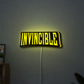 Invincible LED lightbox hanging on a wall with yellow glow