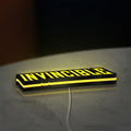 Invincible LED lightbox lying flat on a desk with yellow glow