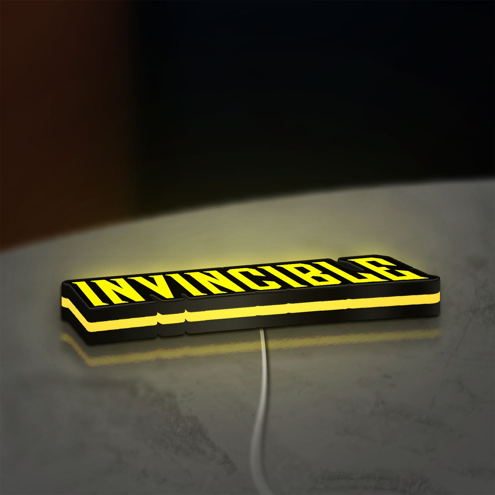 Invincible LED lightbox lying flat on a desk with yellow glow