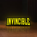 Front view of Invincible LED lightbox sign glowing on a wooden desk
