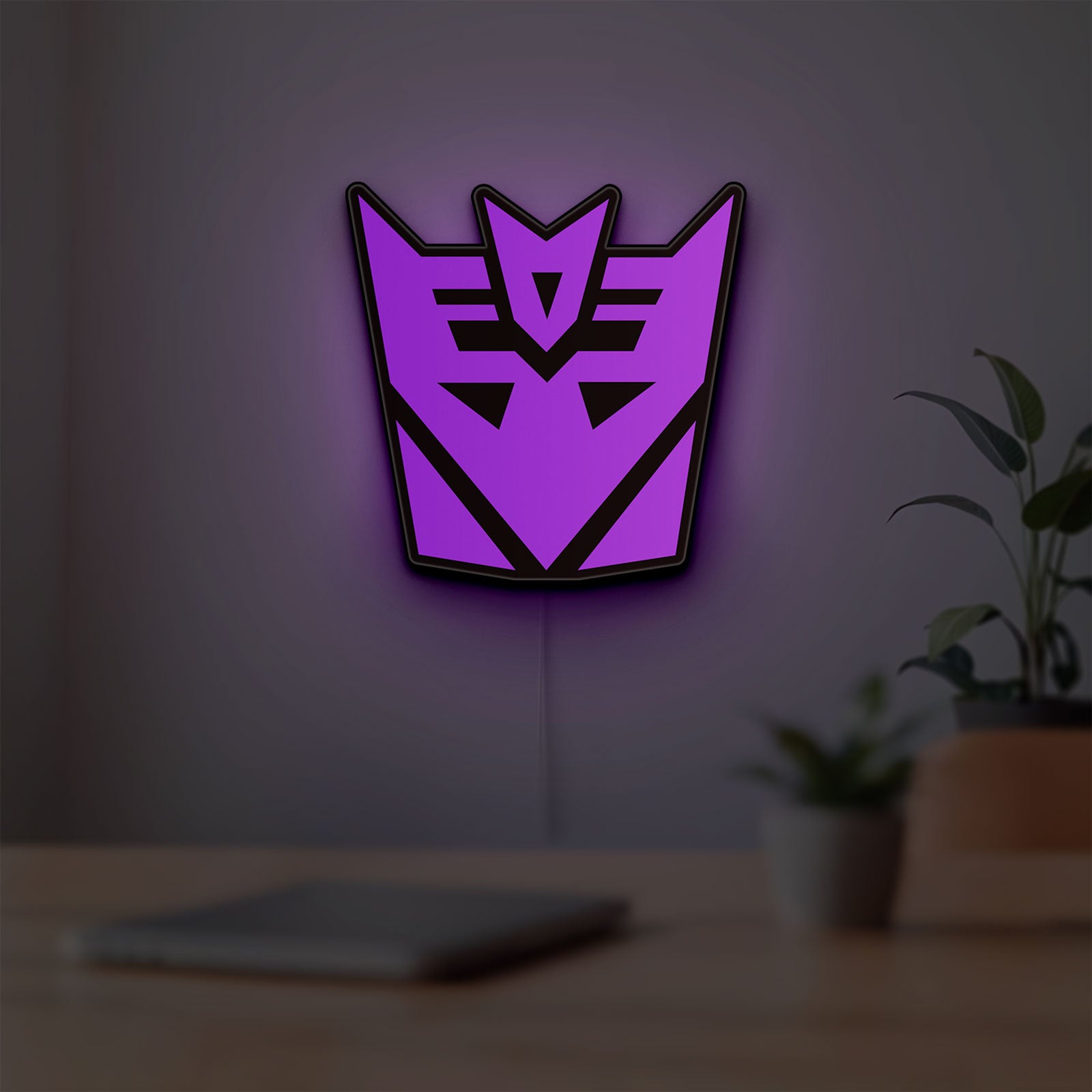 Decepticon LED lightbox hanging on a room wall with soft purple light