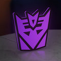 Decepticon LED lightbox standing on a desk from an angled side view with purple glow