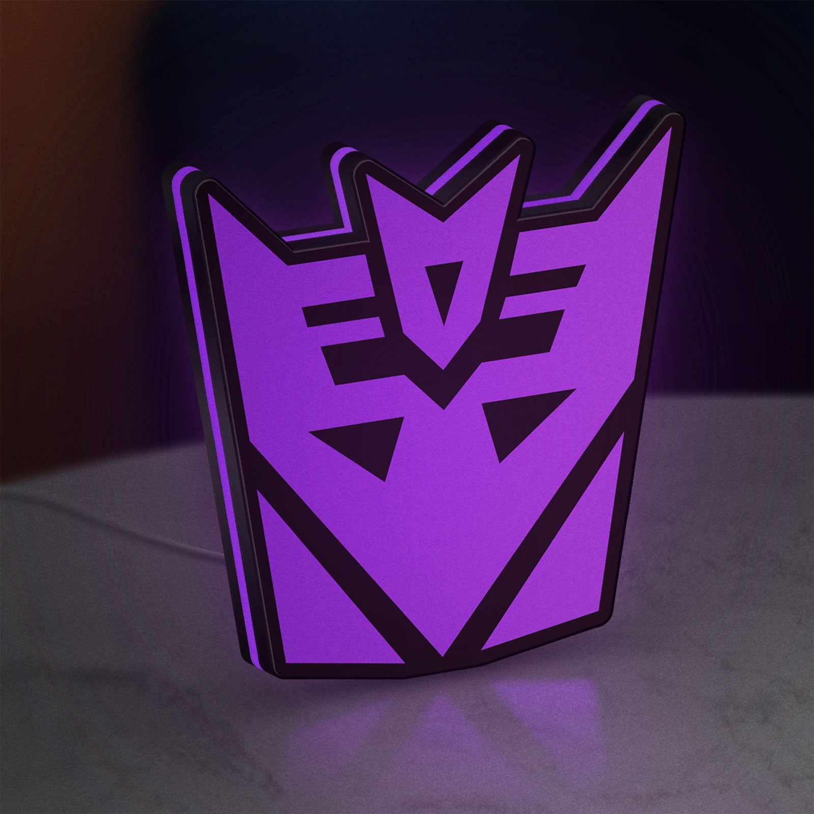 Decepticon LED lightbox standing on a desk from an angled side view with purple glow