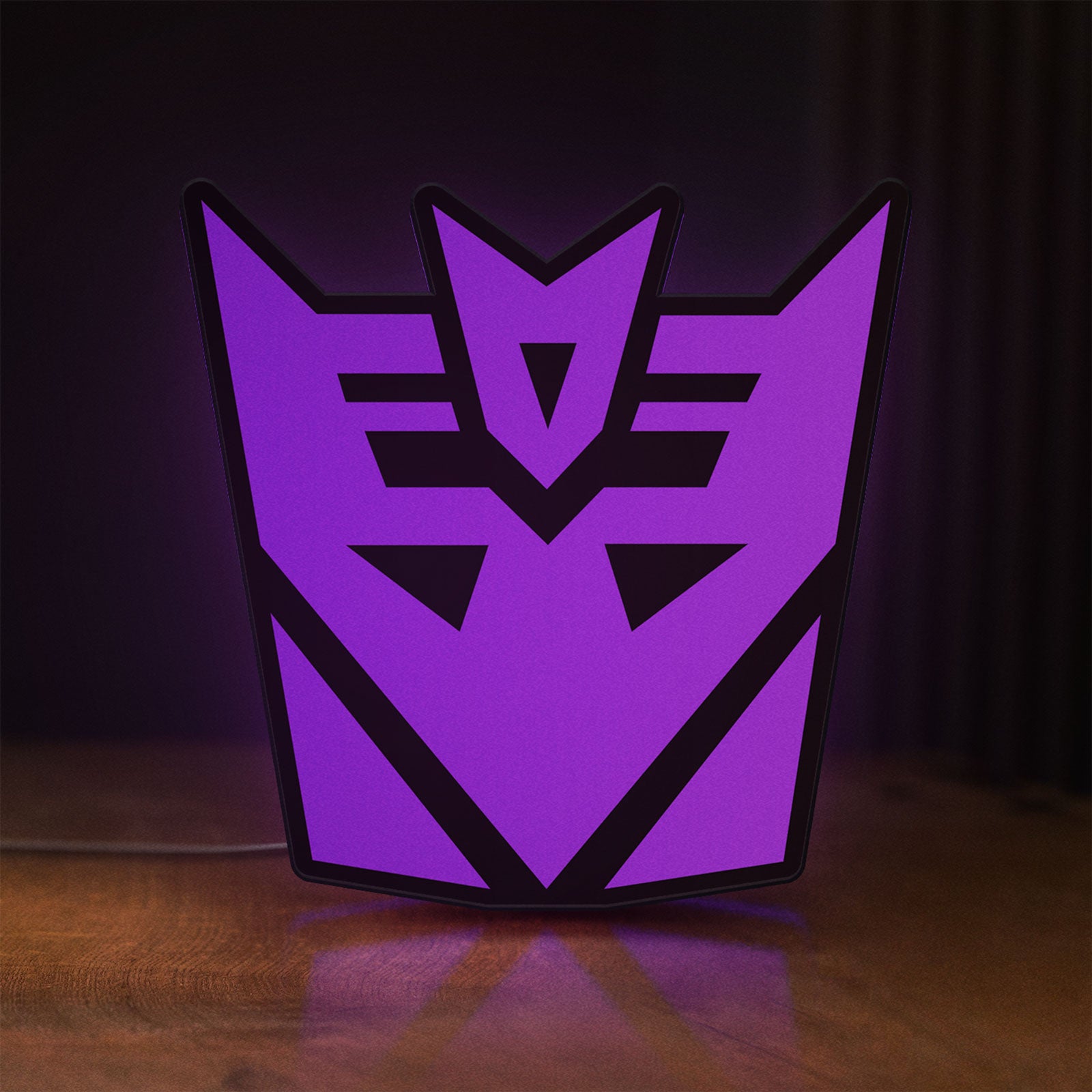 Front view of Decepticon LED lightbox sign glowing on a wooden desk