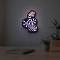 Beetlejuice Sandworm LED lightbox hanging on a room wall with soft purple light