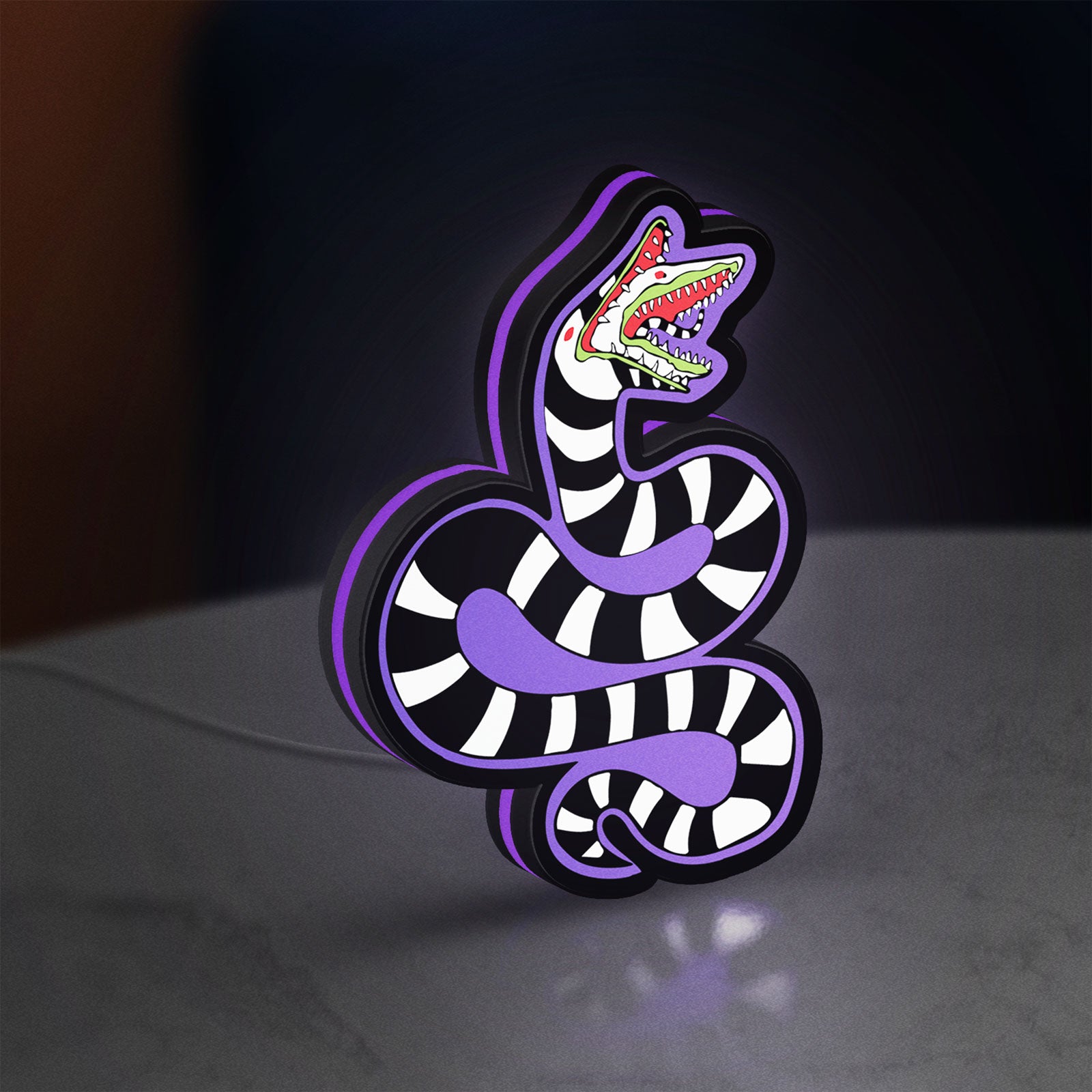 Beetlejuice Sandworm LED lightbox standing on a desk from an angled side view with purple glow