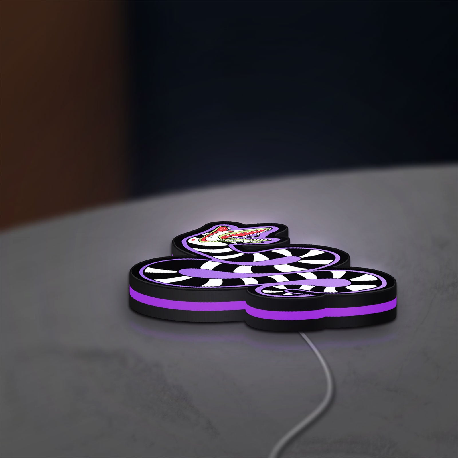 Beetlejuice Sandworm LED lightbox lying flat on a desk with purple glow