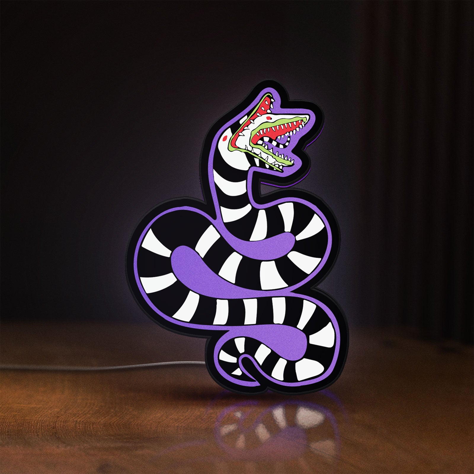 Front view of Beetlejuice Sandworm LED lightbox sign glowing on a wooden desk