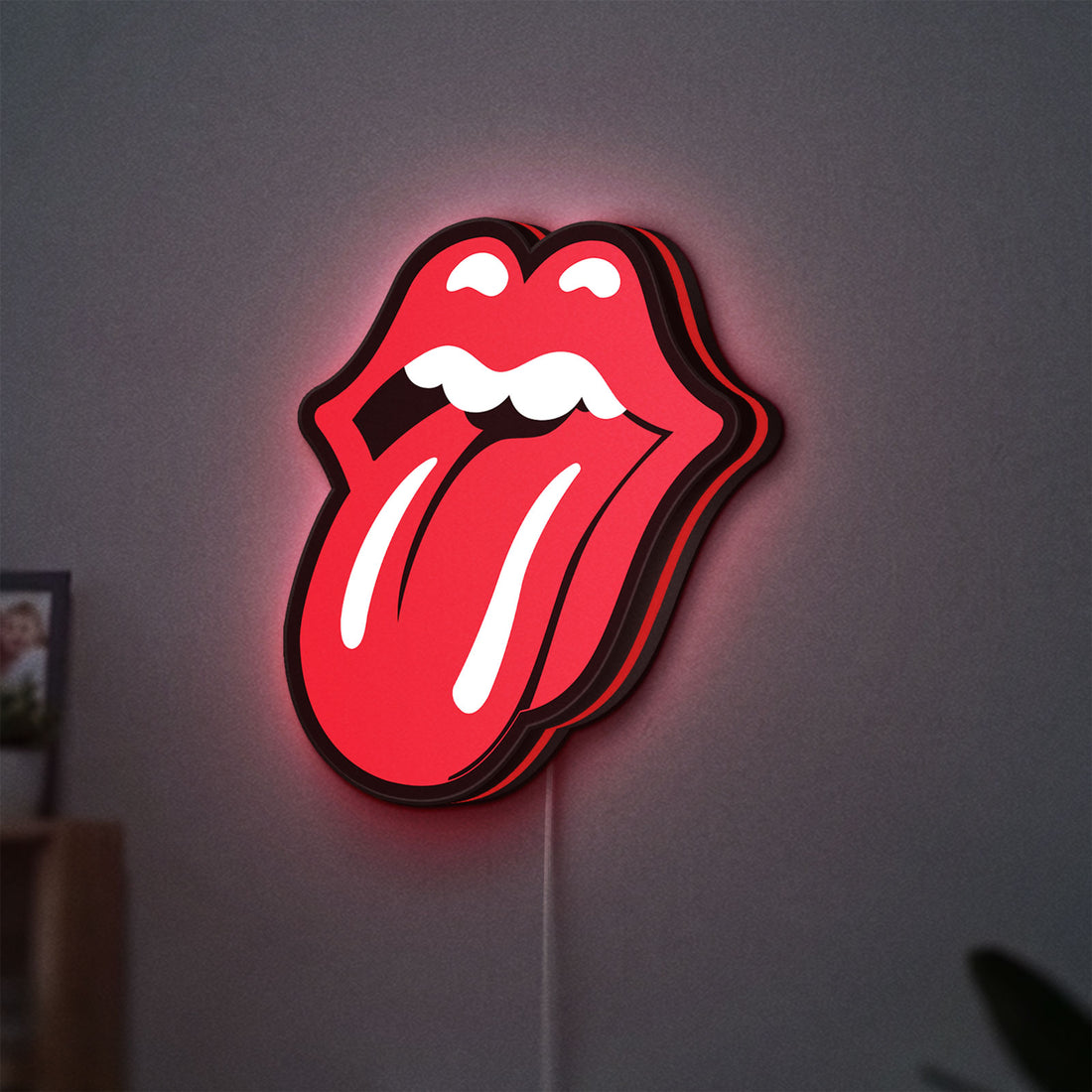 Rolling Stones LED lightbox hanging on a wall with red glow