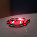 Rolling Stones LED lightbox lying flat on a desk with red glow