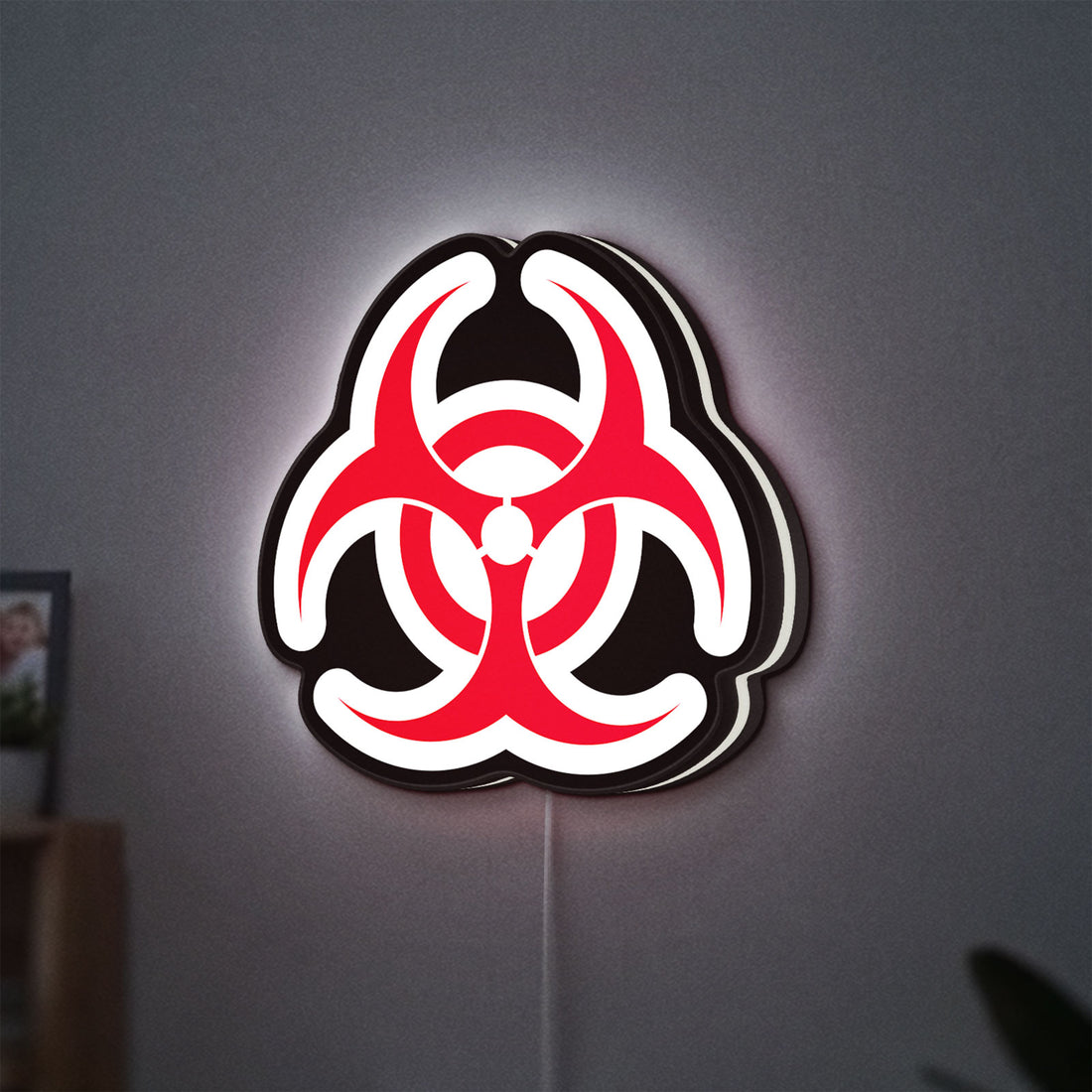 Biohazard LED lightbox hanging on a wall with white glow