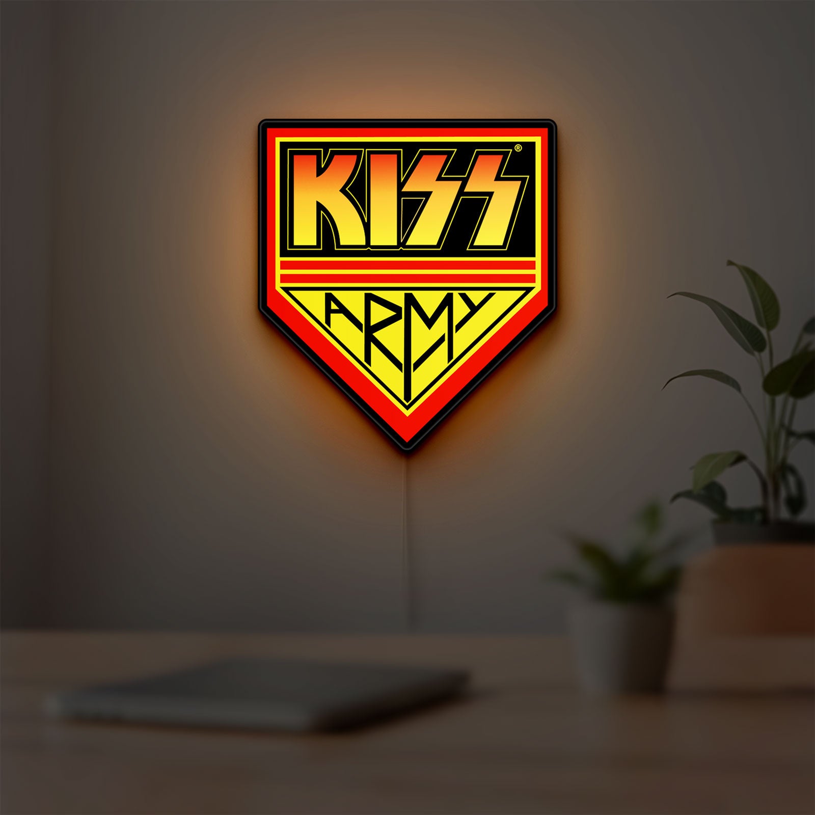 Kiss Army LED lightbox hanging on a room wall with soft yellow light